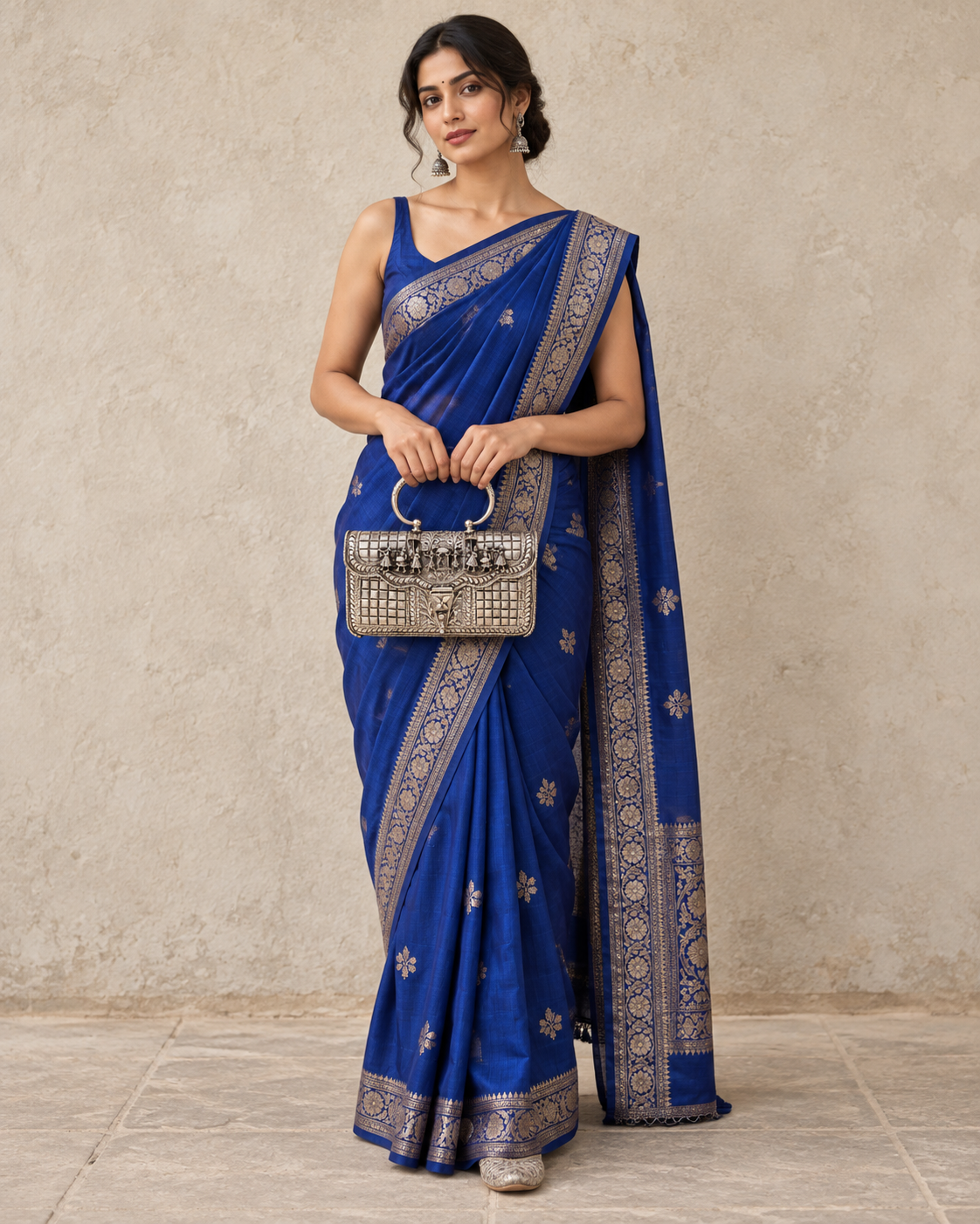 Full-length model in a royal blue saree holding the Baraat silver handbag